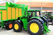 Load image into Gallery viewer, Siku John Deere green and yellow tractor with detachable front loader, shown beside a farm trailer in a realistic farm setting, 1:32 scale model