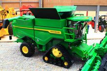 Load image into Gallery viewer, Britains John Deere S7 900 tracked combine harvester model in green with yellow wheels and front header displayed in a miniature farm setting