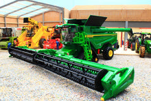 Load image into Gallery viewer, Britains John Deere S7 900 tracked combine harvester model with a wide cutting header displayed among agricultural machinery in a farm showroom
