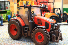 Load image into Gallery viewer, Weathered Britains Kubota M7.154 4WD tractor model in red and black with chunky tyres and front weights displayed in a farm diorama at 1:32 scale