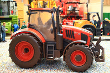 Load image into Gallery viewer, Weathered Britains Kubota M7.154 4WD diecast tractor model in red with enclosed cab and front linkage displayed in a miniature farm scene