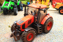 Load image into Gallery viewer, Weathered Britains Kubota M7.154 4WD tractor model in red and black with an enclosed cab and front hitch on a miniature farm display