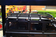 Load image into Gallery viewer, Close up of a dark grey 1 to 18 scale Land Rover Defender 110 model with roof rack and side windows displayed near farm machinery by GT Spirit Models