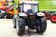 Load image into Gallery viewer, Rear view of a ROS 1 to 32 scale black and white tractor model with large treaded tyres and rear hitch displayed among miniature farm machinery